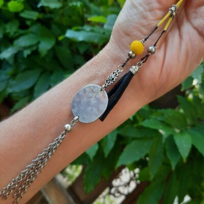 Sautoir pendentif, ajustable, fil de nylon tressé, breloque verre facettée jaune, estampe ronde martelée, chaînettes métal rhodium, pompon suédine noir