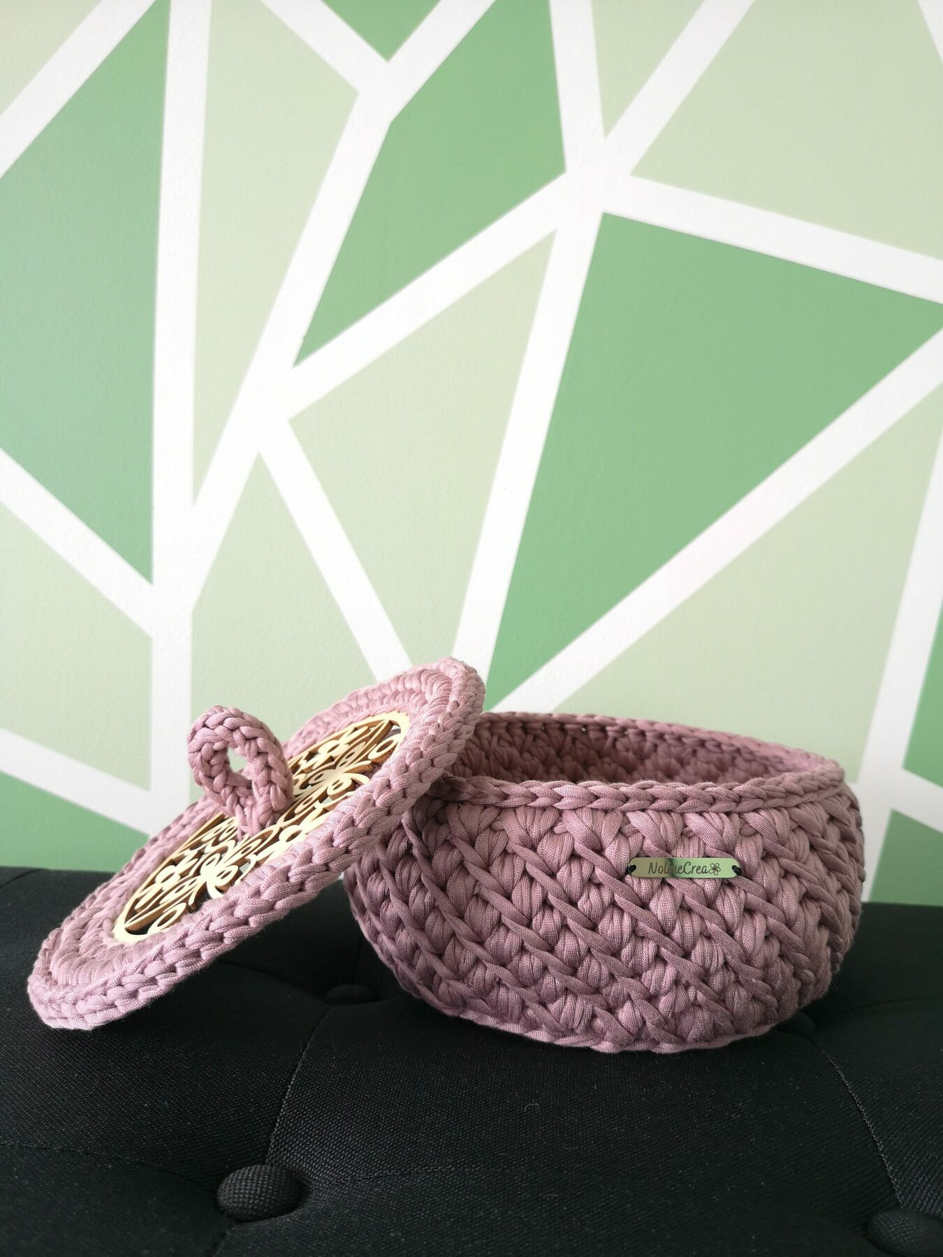 bonbonnière rose posé sur un banc noir, le couvercle du panier est posé à coté de celui-ci