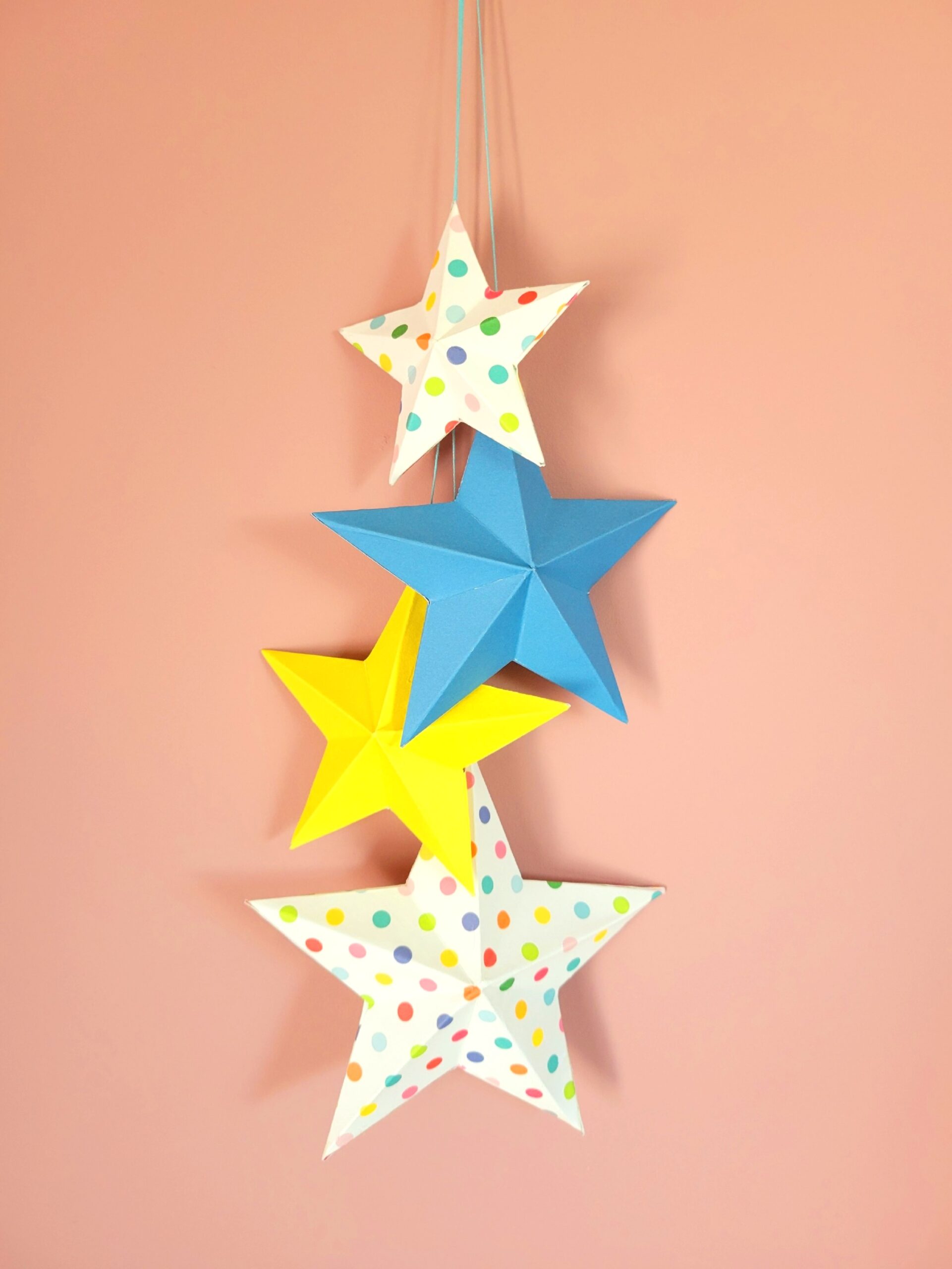 Admirez le contraste saisissant entre les étoiles suspendues colorées et le mur rose poudré. Cette décoration étoile suspendue de 50cm crée un point focal captivant qui égaye instantanément la pièce.
