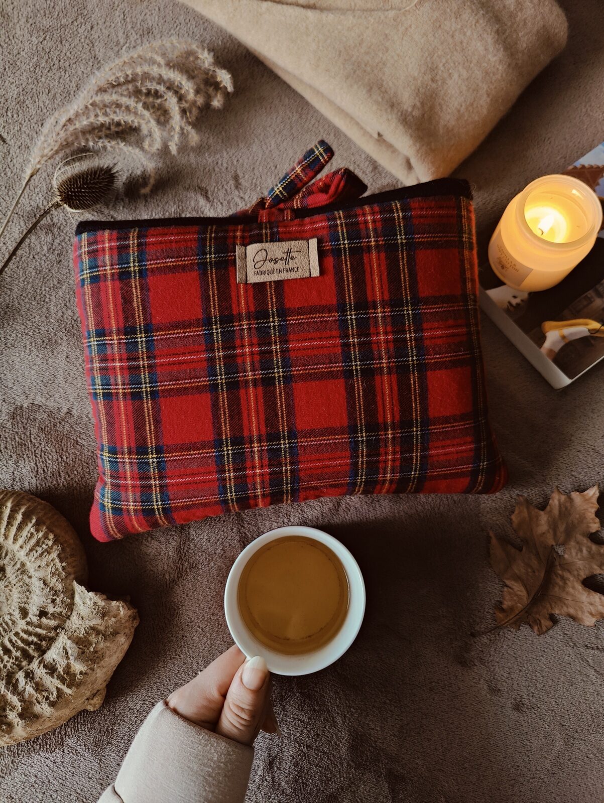 Pochette à livre en tissu tartan rouge à carreaux posée dans un décor cosy avec tasse de thé.
