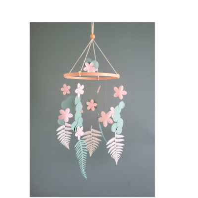 Mobile bébé fleurs de cerisier et eucalyptus en papier recyclé suspendu sur fond gris.