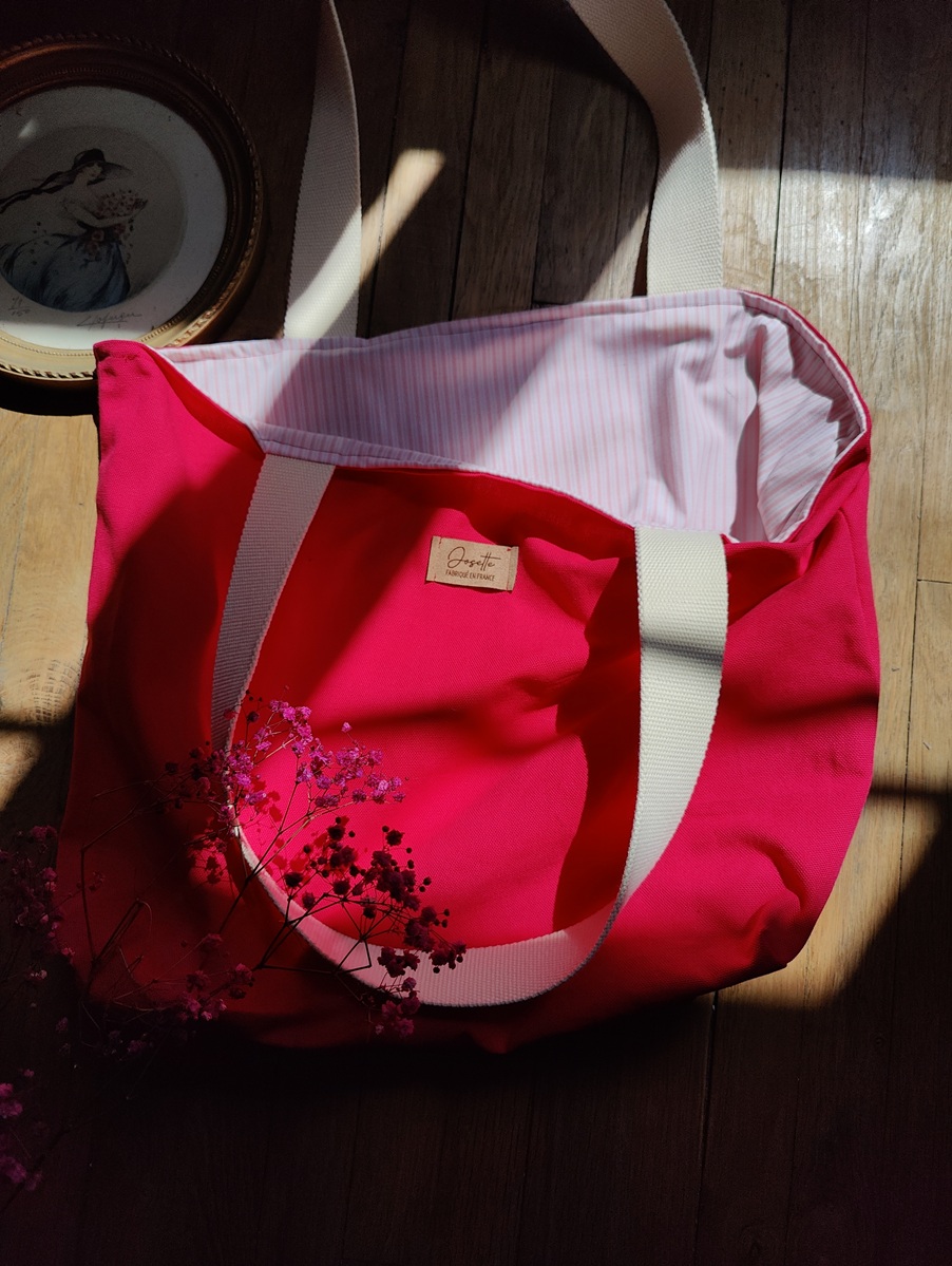Tote bag réversible upcyclé retourné, montrant le côté fuchsia et les anses en coton beige.