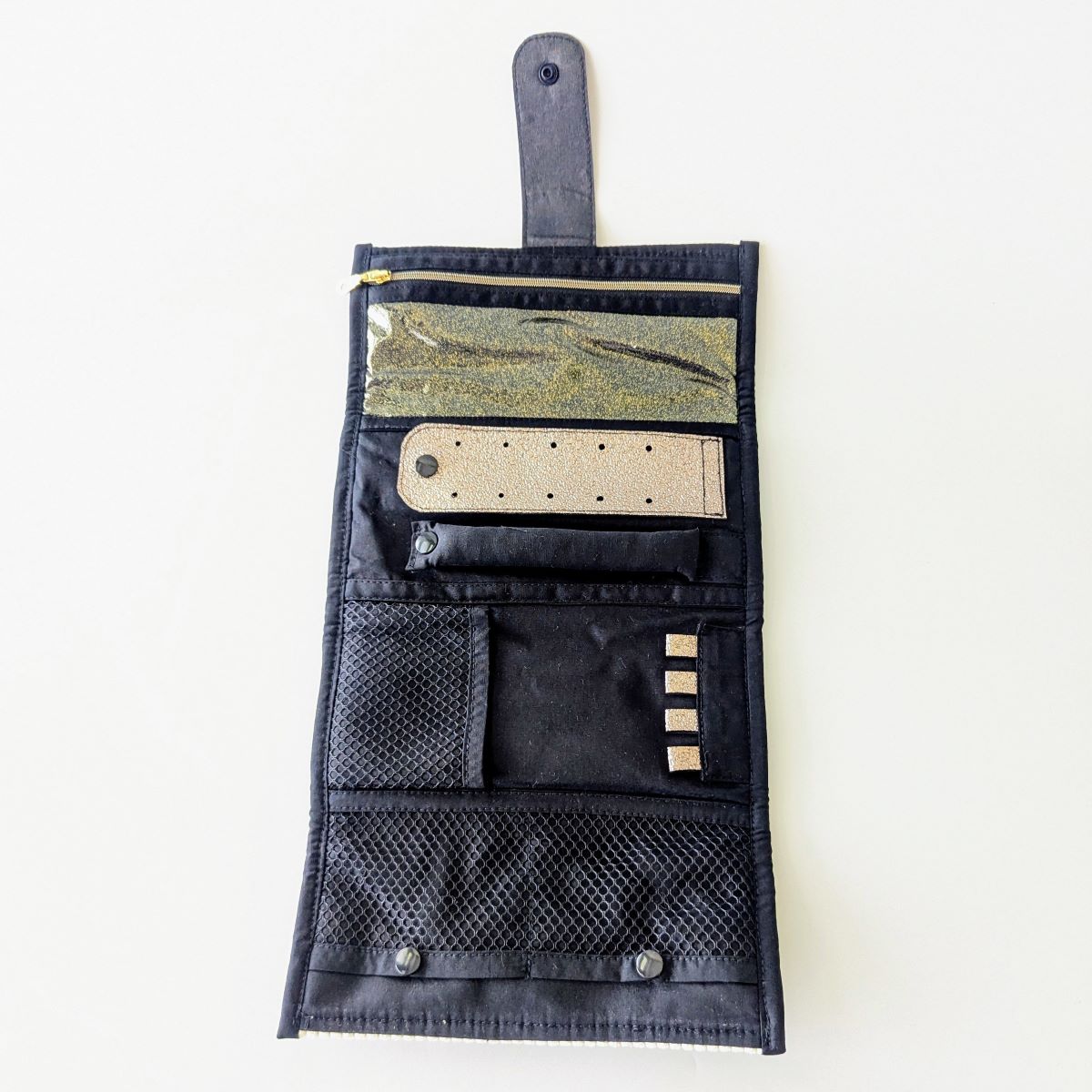 Détail intérieur de la pochette à bijoux — panneau droit avec 2 poches à boutons pression, filet mesh décoratif et 4 attaches colliers galuchat bronze