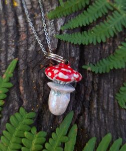 Magnifique pendentif cachette sculpté à la main en forme de champignon amanite, doté d'un chapeau amovible qui se dévisse pour cacher de petits secrets. Cette pièce unique brille délicatement dans le noir et sous la lumière ultraviolette, offrant un effet magique et envoûtant.
Pendentif : 2 x 3 cm  
Chaîne : 45 cm  
Acier inoxydable, argile polymère, résine époxy  
Rouge éclatant, blanc, reflets nacrés et détails lumineux  
Livré dans une jolie boîte cadeau prête à offrir  
Le chapeau se dévisse pour révéler un petit compartiment secret ; brille dans le noir et aux UV  
Psychédélique, cottagecore, forestier, bohème, goblin core, féerique, alternatif  